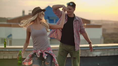 Loving-couple-in-plaid-shirts-dance-on-the-roof.-Girl-with-beer-spinning-in-dance-with-her-boyfriend.